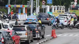 Pedagang asongan menjajakan barang dagangannya di persimpangan lampu merah di Jakarta, Jumat (22/2). Keahlian yang terbatas menyebabkan sebagian orang harus bekerja di tengah padatnya kendaraan Ibukota. (Liputan6.com/Immanuel Antonius)