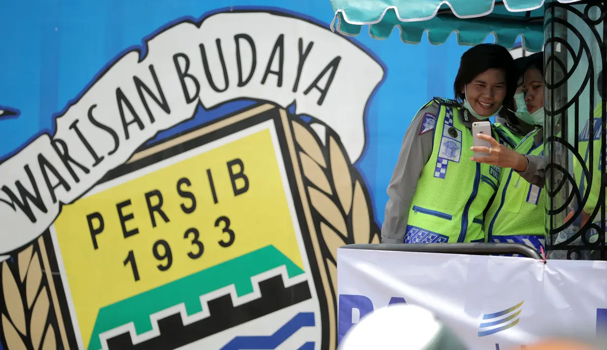 Polwan (Polisi Wanita) berfoto selfie sebelum melakukan pengamanan parade Juara Piala Presiden 2015 di Kota baru, Bandung, Minggu (25/10/2015). (Bola.com / Nicklas Hanoatubun)