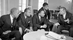 Presiden Lyndon B. Johnson (kanan) berbicara dengan Martin Luther King dan para pemimpin hak-hak sipil di Gedung Putih, Washington, 18 Januari 1964. Pembunuhan terhadap King dilakukan saat dia berdiri di balkon hotelnya. (AP Photo/File)