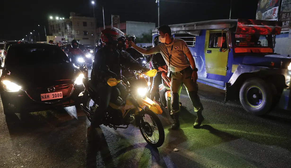 Petugas lalu lintas memeriksa suhu tubuh pengendara sepeda motor di pos pemeriksaan virus corona COVID-19 di Manila, Filipina, Senin (16/3/2020). Polisi beserta petugas lalu lintas dan petugas desa mengecek suhu tubuh warga untuk mencegah penyebaran virus corona COVID-19. (AP Photo/Aaron Favila)