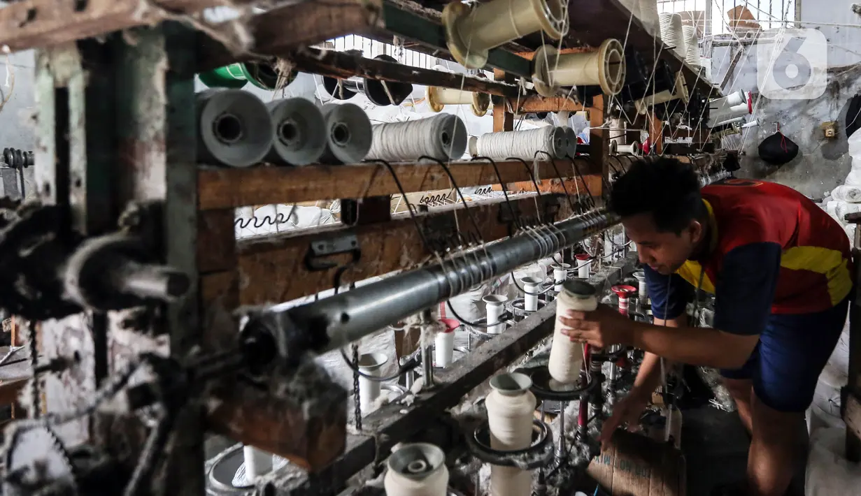 Pekerja memintal benang di Kebayoran, Jakarta, Selasa (5/7/2022). Pabrik benang yang berdiri sejak tahun 1970-an tersebut dapat memproduksi 100 kilogram benang dalam sehari dan dipasarkan ke berbagai daerah di Indonesia. (Liputan6.com/Johan Tallo)