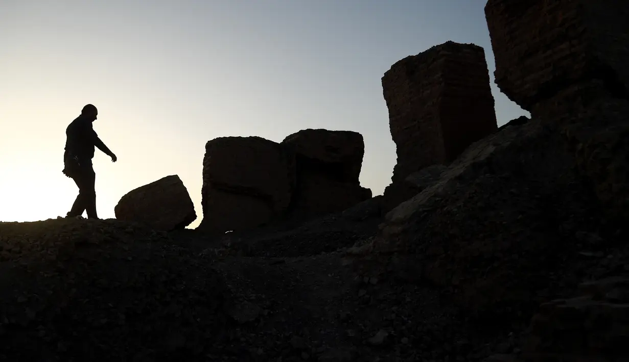 Seorang pria saat mengunjungi situs arkeologi Babilonia, Irak, Minggu (21/3/2021). Irak berupaya memasukkan kota yang disebut sebagai tempat lahirnya peradaban dalam Situs Warisan Dunia sejak tahun 1983. (AP Photo/Hadi Mizban)
