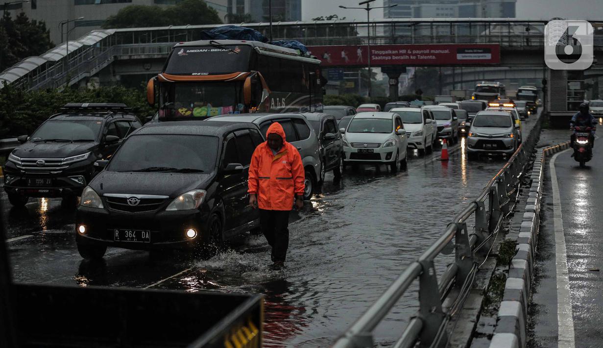 Petugas berjalan di antara kendaraan yang terjebak kemacetan di ruas Tol Dalam Kota (Dalkot), Jakarta, Selasa (17/12/2019). Air hujan sempat menggenangi sebagian ruas Tol Dalam Kota  untuk arah Kuningan arah Cawang hingga sempat membuat lalu lintas tersendat. (Liputan6.com/Faizal Fanani)