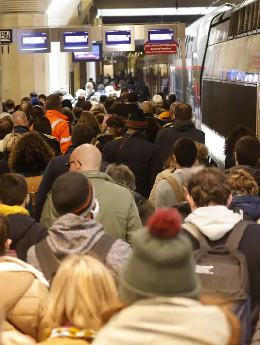 Warga Paris berjalan di sepanjang peron untuk naik kereta yang berangkat dari Gare Montparnasse di Paris, Jumat (19/3/2021). Warga Paris memadati kereta antar kota yang berangkat dari ibu kota beberapa jam sebelum lockdown selama sebulan untuk memerangi lonjakan infeksi COVID-19. (Ludovic MARIN/AFP)