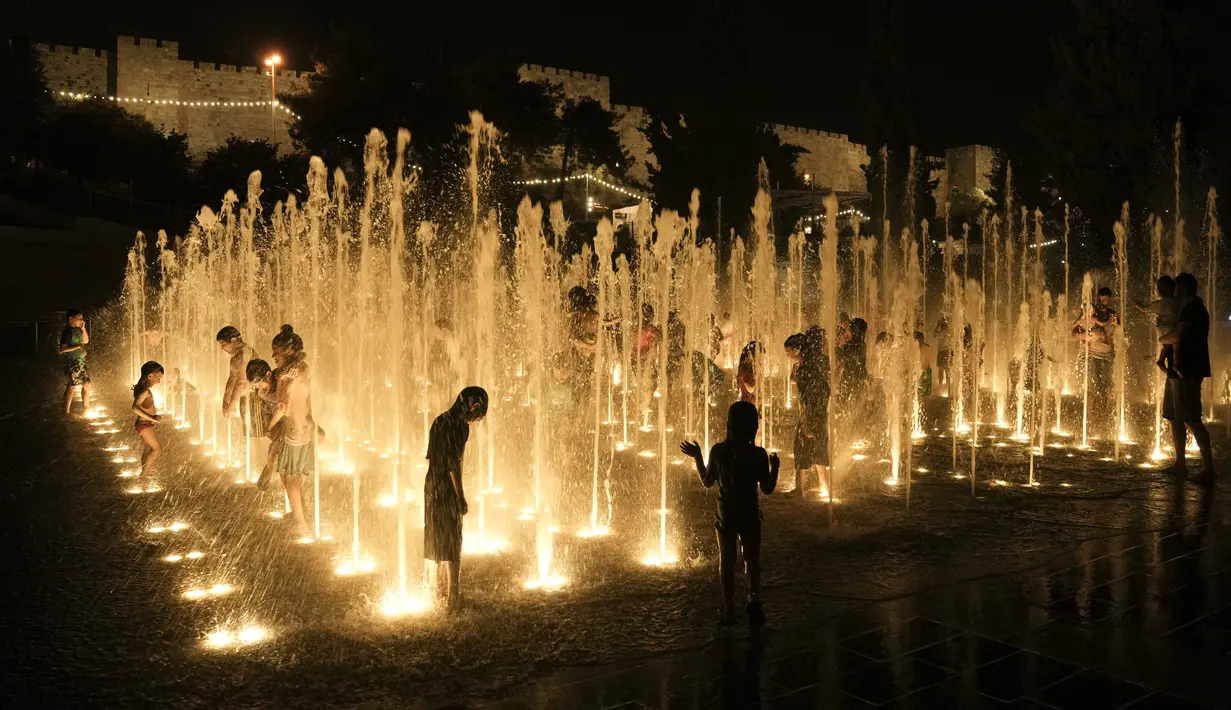 Orang-orang mendinginkan diri di air mancur di luar Kota Tua Yerusalem, Senin, 29 Agustus 2022. Israel dan wilayah Palestina berada dalam cengkeraman gelombang panas minggu ini, dengan suhu mencapai 40 Celcius (104 derajat Fahrenheit) di Yerusalem, dan 45 Celcius (113 derajat Fahrenheit) di Lembah Yordan. (AP Photo/Mahmoud Illean)