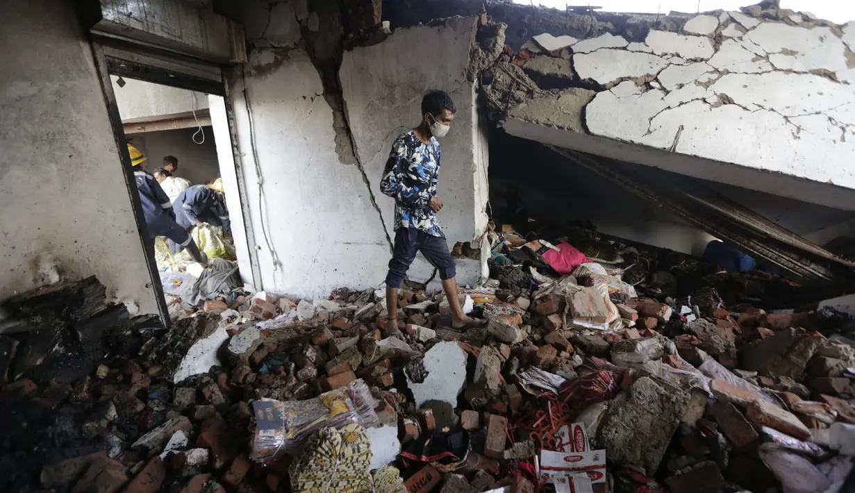 Seorang pria berjalan di atas puing-puing di lokasi kebakaran di sebuah pabrik di kawasan industri di pinggiran Ahmedabad, India (4/11/2020). Menurut pejabat setempat, puluhan orang tewas ketika sebagian gudang bahan kimia runtuh setelah terjadi ledakan dahsyat. (AP Photo/Ajit Solanki)