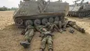Pasukan Tentara Israel tidur di tanah di samping kendaraan lapis baja di perbatasan Israel dengan Jalur Gaza. (REUTERS / Nir Elias)