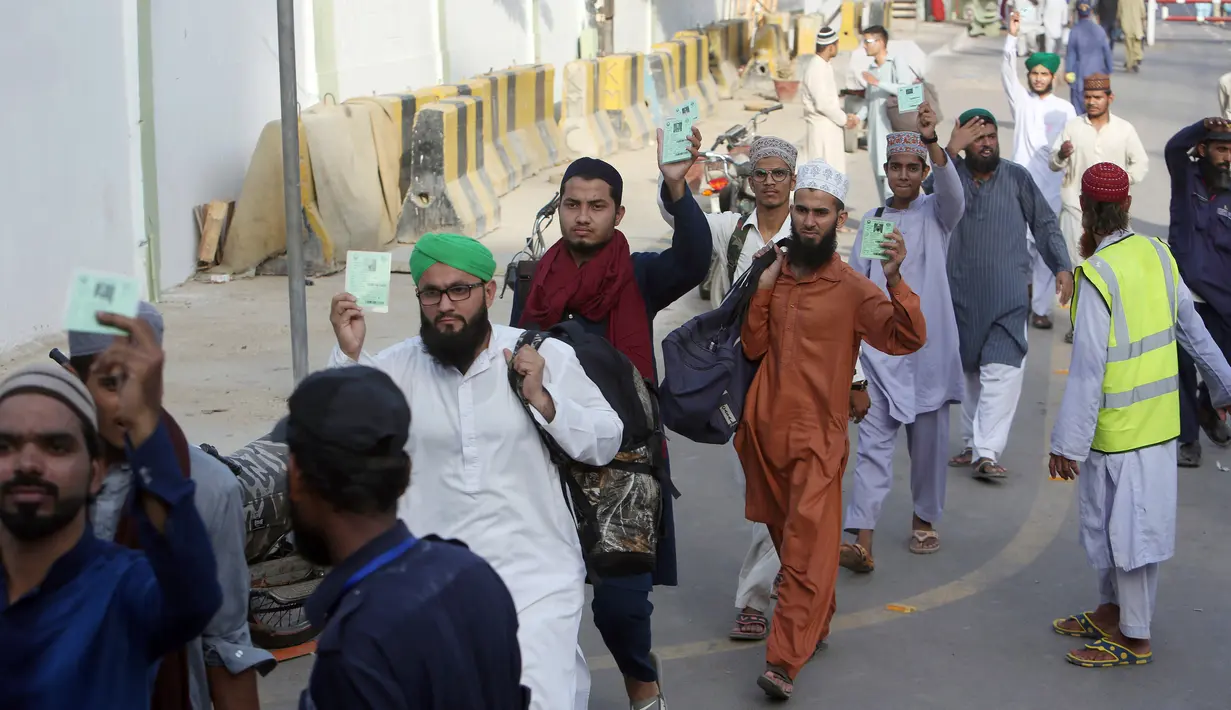 Umat muslim memperlihatkan kartu mereka ketika tiba untuk mengamati itikaf atau berdiam di masjid dan menyembah Allah pada sepuluh hari terakhir bulan Ramadan di sebuah masjid di Karachi, Pakistan, Minggu (26/5/2019). (AP Photo/Fareed Khan)