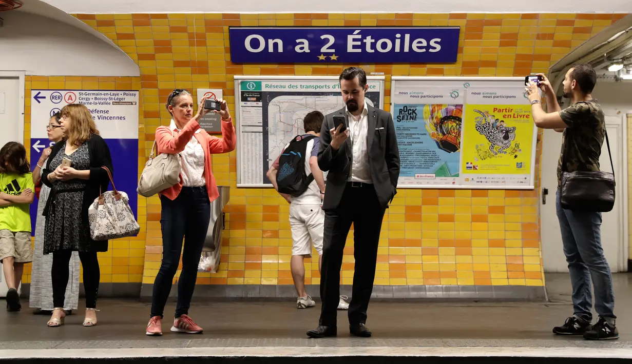 Calon penumpang mengambil gambar tanda bertuliskan "On a deux etoiles" di stasiun metro Etoile, Paris, Senin (16/7). Enam stasiun utama di Paris untuk sementara diganti namanya guna menghormati Prancis yang menjadi juara Piala Dunia. (AFP/Thomas SAMSON)