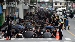 Sejumlah warga mengenakan pakaian hitam memadati jalan saat saat menunggu pemakaman mendiang Raja Thailand Bhumibol Adulyadej di Bangkok (25/10). (AFP Photo/Roberto Schmidt)