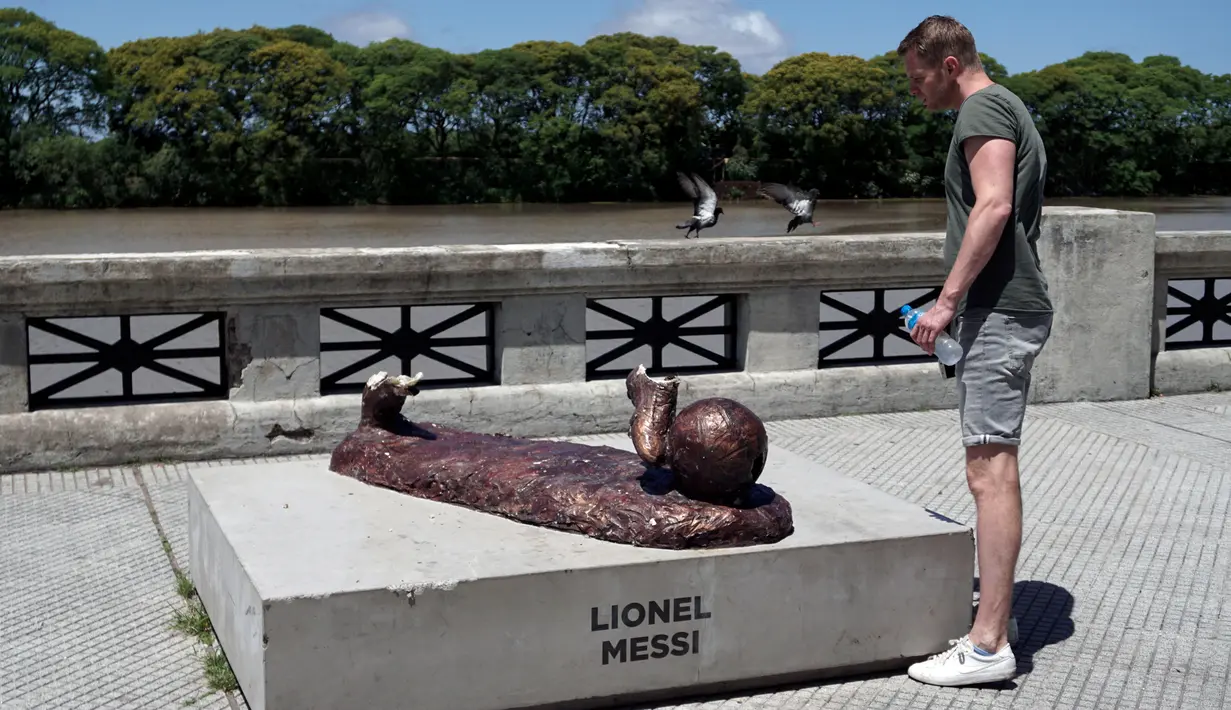 Seorang pria melihat patung Lionel Messi yang kembali menjadi sasaran aksi perusakan di Buenos Aires, Argentina, Senin (4/12). Pelaku perusakan merobohkan patung Messi yang terbuat dari perunggu dengan menghancurkan kedua kakinya. (EITAN ABRAMOVICH/AFP)