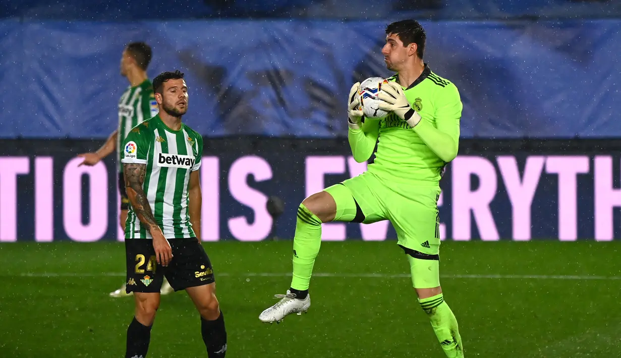 Kiper Real Madrid, Thibaut Courtois (kanan) menangkap bola dari ancaman striker Real Betis, Aitor Ruibal dalam laga lanjutan Liga Spanyol 2020/2021 pekan ke-33 di Alfredo Di Stefano Stadium, Madrid, Sabtu (24/4/2021). Real Madrid bermain imbang 0-0 dengan Real Betis. (AFP/Gabriel Bouys)
