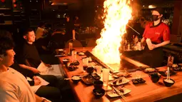 Pengunjung menikmati hidangan teppanyaki Jepang di Chinatown, Melbourne, Australia, Jumat (22/10/2021). Melbourne melonggarkan kebijakan lockdown mulai hari ini setelah berlangsung lebih dari 260 hari. (William WEST/AFP)