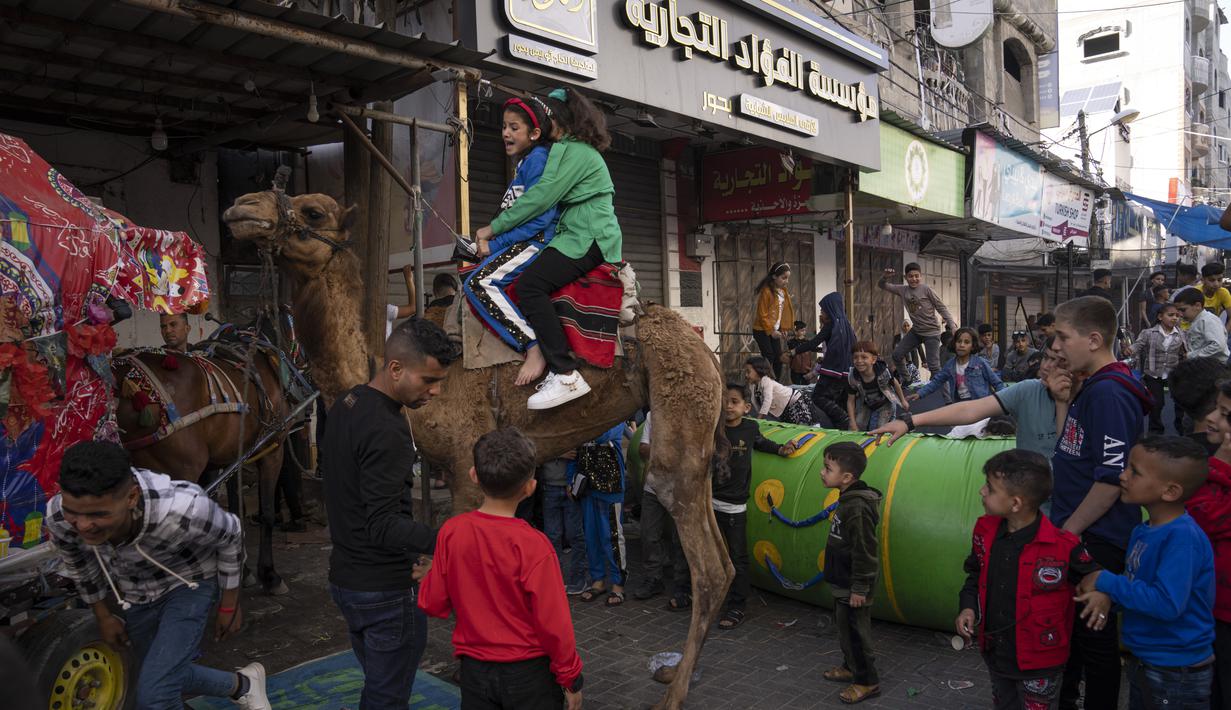 Selain aneka permainan, anak-anak juga bisa naik unta. (AP Photo/Fatima Shbair)