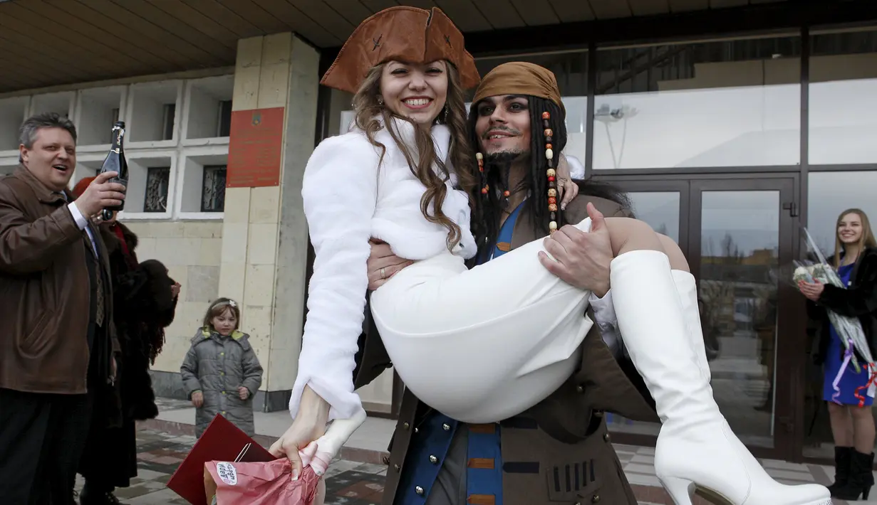 Yesakov membawa istrinya saat upacara pernikahan mereka di selatan kota Stavropol, Rusia, (5/2/2016). Yesakov menyiapkan pesta pernikahan bertema 'Pirates of the Caribbean' sebagai kejutan untuk Anastasiya. (REUTERS/Eduard Korniyenko)