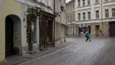 Seorang kurir pengiriman makanan yang mengenakan masker untuk mencegah penyebaran virus corona, mengendarai sepeda di Kota Tua, Vilnius, Lithuania (7/11/2020). Penguncian dilakukan untuk membendung penyebaran virus corona. (AP Photo/Mindaugas Kulbis)