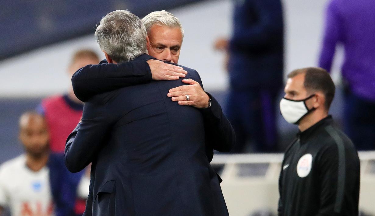 Pelatih Tottenham Hotspur, Jose Mourinho, berpelukan dengan pelatih Everton, Carlo Ancelotti, pada laga Premier League, Senin (6/7/2020). Mourinho melanggar aturan jarak sosial demi memeluk Carlo Ancelotti yang merupakan idolanya. (AFP/Adam Davy)