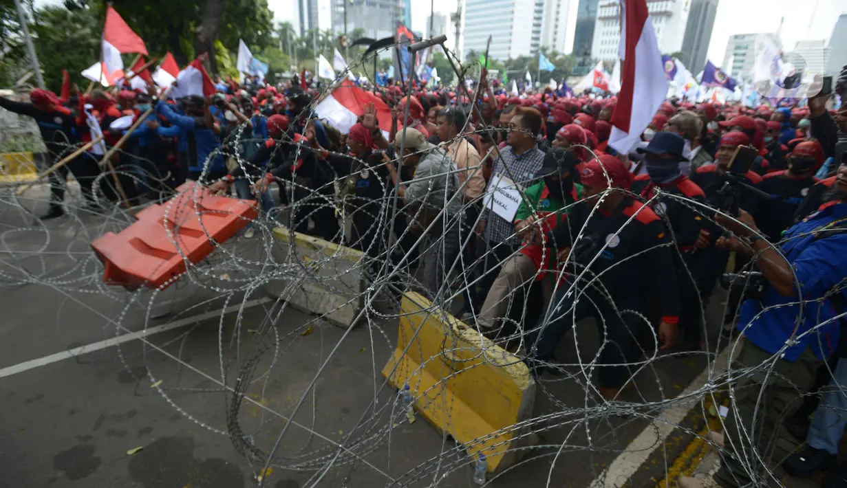 Pengunjuk rasa dari berbagai elemen buruh berusaha menerobos kawat berduri dalam aksi unjuk rasa di kawasan Patung Kuda, Jakarta, Rabu (8/12/2021). Dalam aksinya tersebut mereka meminta pemerintah dan DPR mencabut Undang-undang Nomor 11 Tahun 2020 tentang Cipta Kerja. (merdeka.com/Imam Buhori)