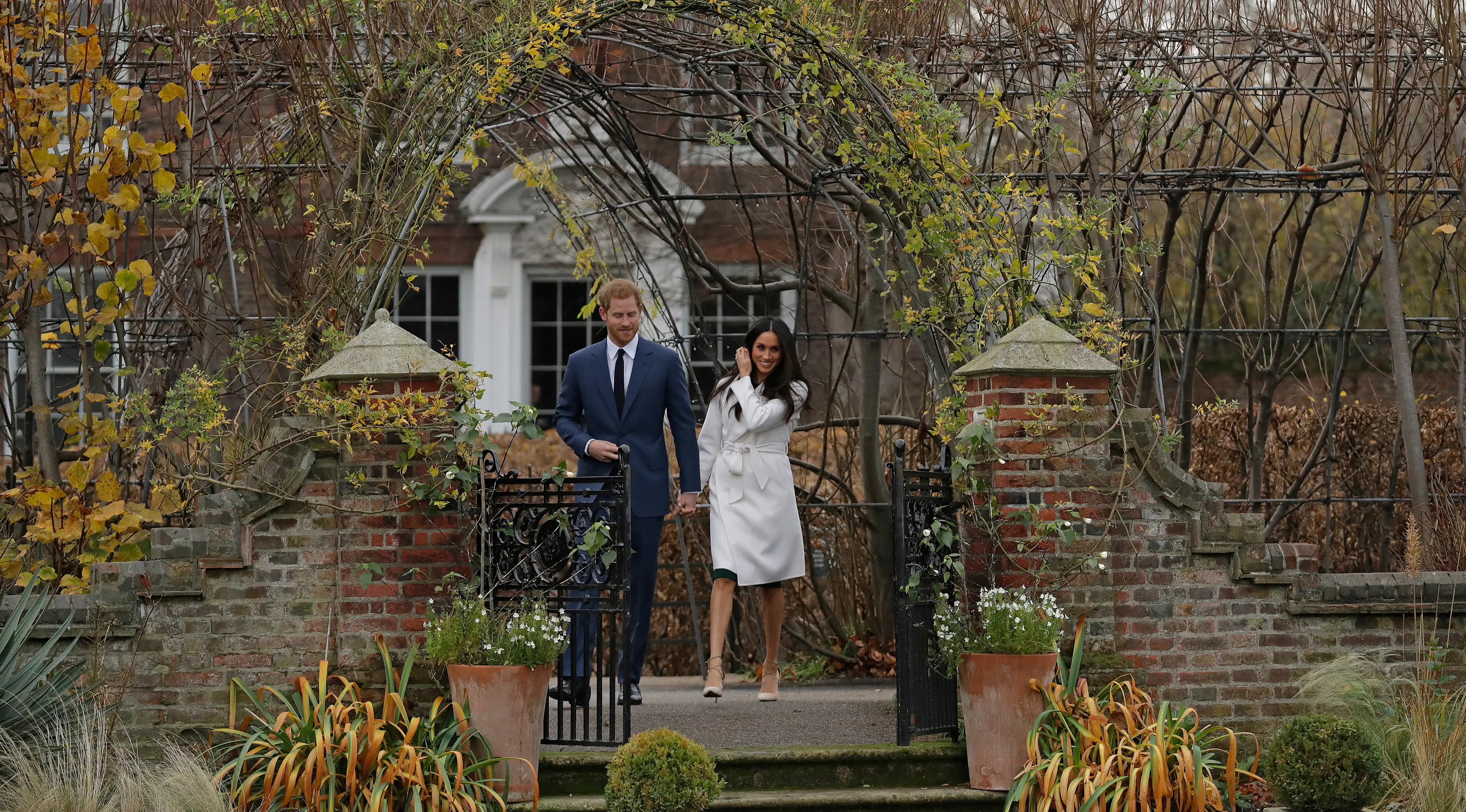 Pangeran Harry dan aktris AS, Meghan Markle berjalan untuk mengumumkan pertunangan mereka kepada media di Kensington Palace, London, Senin (27/11). Pangeran Harry dan Meghan Markle bertunangan di London pada awal November ini. (AP/Matt Dunham)