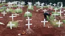 Pekerja sedang melakukan perawatan lokasi pemakaman jenazah yang diduga terinfeksi Covid-19 di TPU Pondok Ranggon, Jakarta, Kamis {30/4/2020). Sejumlah makam terlihat mulai dipasangi rumput dan batu nisan. (Liputan6.com/Helmi Fithriansyah)