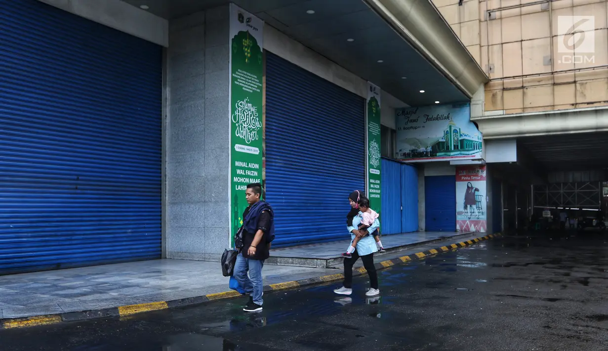 Warga melintasi sejumlah kios yang tutup pada hari ketiga Lebaran di Blok B Pasar Tanah Abang, Jakarta, Jumat (7/6/2019). Selepas Hari Raya Idul Fitri, Pasar Tanah Abang masih tutup dan direncanakan buka pada Kamis (13/6) mendatang. (Liputan6.com/Johan Tallo)