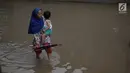 Seorang warga menggendong anak melintasi banjir yang merendam kawasan Cipinang Melayu, Jakarta Timur, Senin (5/2). (Liputan6.com/Arya Manggala)