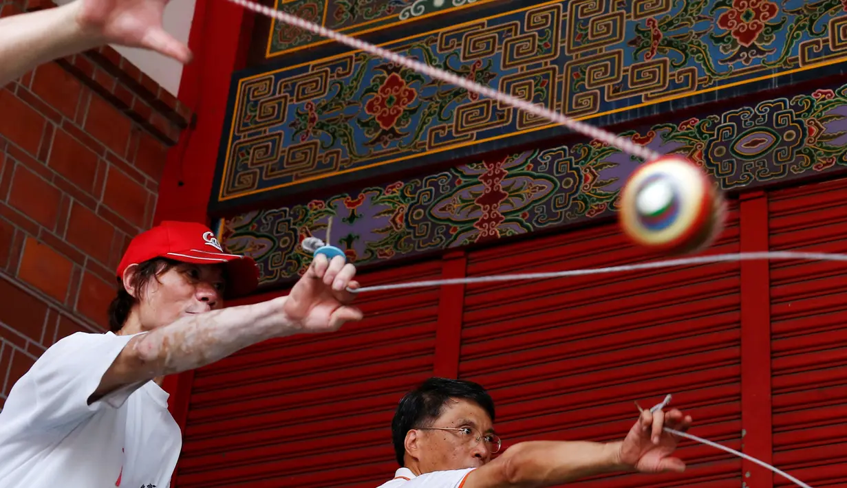 Sejumlah peserta ketika memainkan gasing dalam turnamen gasing di New Taipei City, Taiwan (9/5). Dalam turnamen ini peserta menampilkan sejumlah trik mengagumkan. (REUTERS/Tyrone Siu)