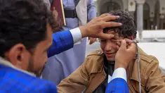 Seorang pria Yaman mengoleskan kosmetik tradisional Kohl ke kelopak mata remaja selama bulan puasa Ramadhan di Masjid Sanaa (16/4/2021).  Di Yaman, salah satu tradisi khas menandai Ramadhan yang masih lestari adalah aksi para pemuda yang merias mata dengan kohl. (AFP/ Mohammed Huwais)