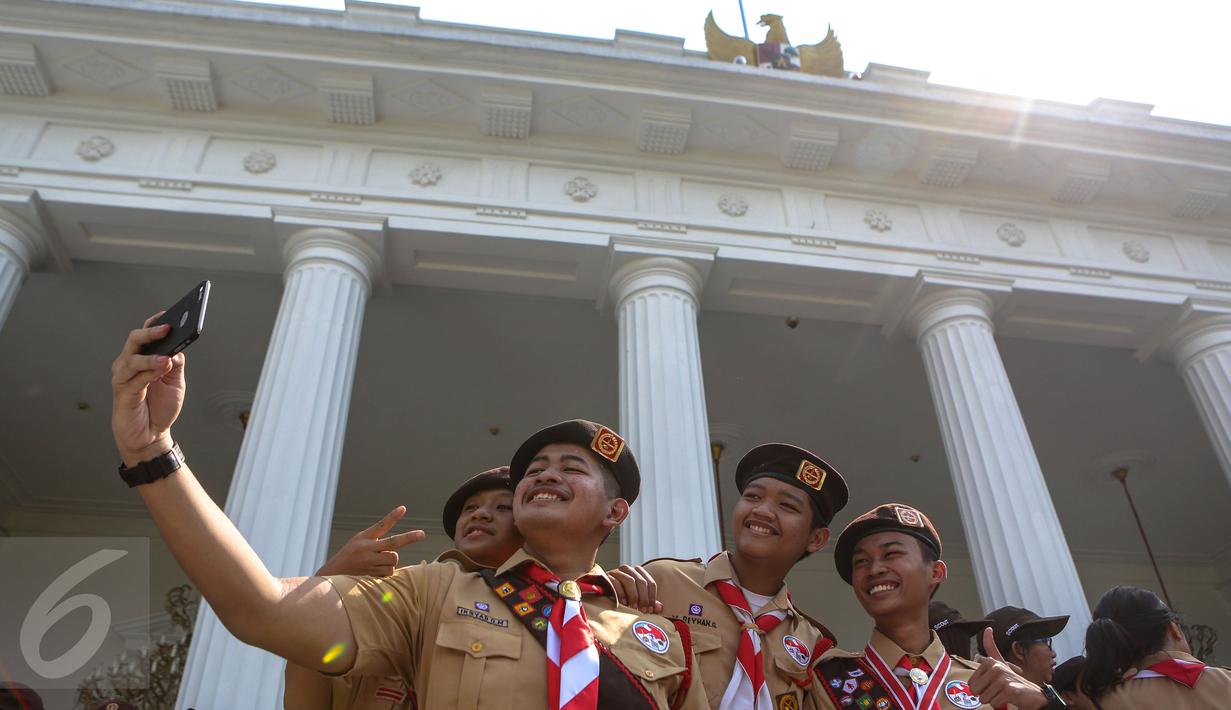  Seorang Pria asik berfoto dengan teman – temannya di Halaman Istana Merdeka, Jakarta, Jumat (24/7/2015). Presiden Jokowi melepas 462 kontingen Pramuka Indonesia ke jepang untuk berkiprah di Jambore Dunia ke-23. (Liputan6.com/Faizal Fanani)
