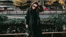 Sebagai inti dari penampilannya, ia mengenakan trench coat kulit hitam berpotongan panjang yang memberikan kesan edgy sekaligus timeless. Coat ini dipadukan dengan turtleneck sweater hitam, dan celana hitam berpotongan lurus. [@aaliyah.massaid].