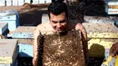 Mohamed Hagras bersiap untuk dikerumuni ratusan lebah, Mesir (30/11). Menurut Hagras, lebah membantu dan menghasilkan banyak manfaat untuk manusia dan pertanian. (Reuters/Amr Abdallah Dalsh)