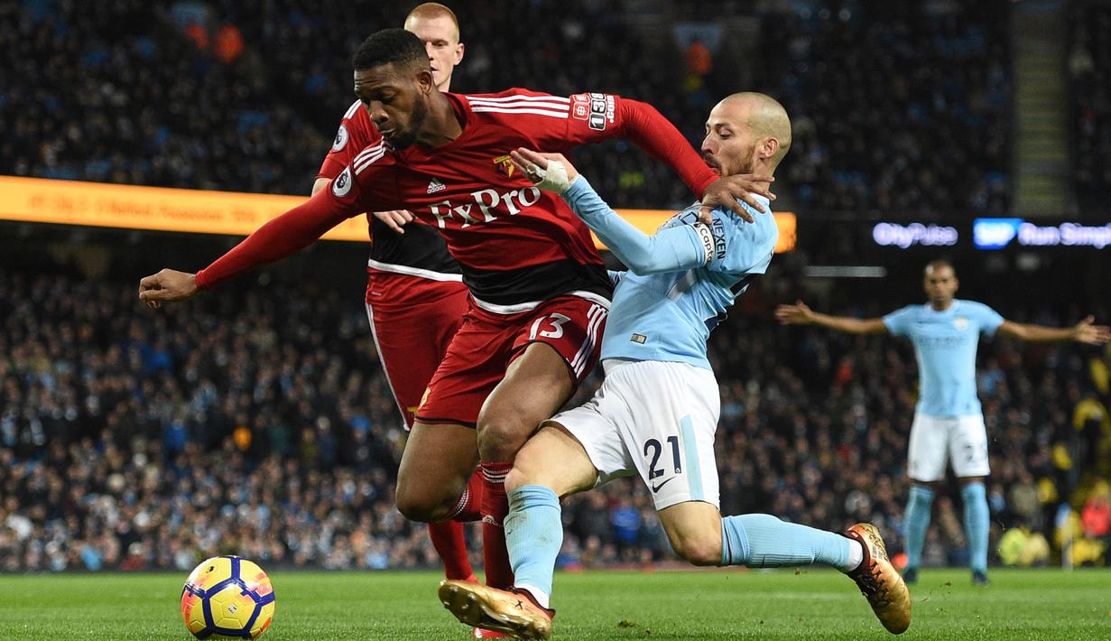 Pemain Watford, Kiko Femenia (kiri) berusaha menahan laju pemain Manchester City, David Silva saat berebut bola pada lanjutan Premier League di Etihad stadium, Manchester, (2/1/2018).  City menang 3-1. (AFP/ Oli Scarff)