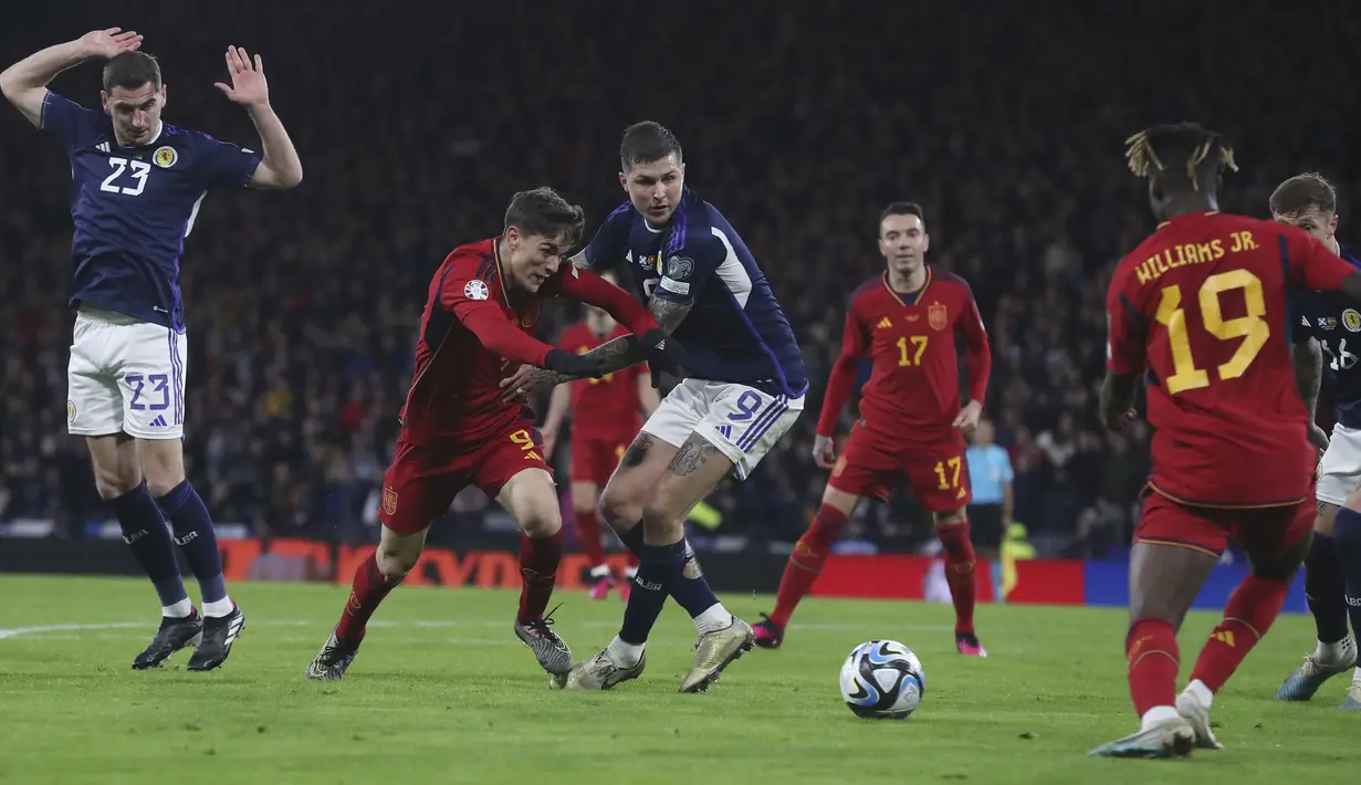 Pemain Spanyol, Gavi (tengah kanan) berebut bola dengan pemain Skotlandia, Lyndon Dykes pada matchday kedua Kualifikasi Euro 2024 di Hampden Park, Glasgow, Skotlandia, Rabu (29/03/2023) WIB. Skotlandia berhasil menang dengan skor 2-0. (AP Photo/Scott Heppell)