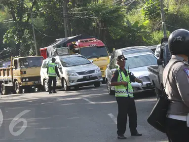 Petugas berusaha mengatur kemacetan kendaraan yang melintas di jalur lingkar Nagreg, Jawa Barat, Sabtu (2/7). Kemacetan disebabkan bus pemudik yang mengalami kecelakaan hingga menutup sebagian jalur. (Liputan6.com/Immanuel Antonius)