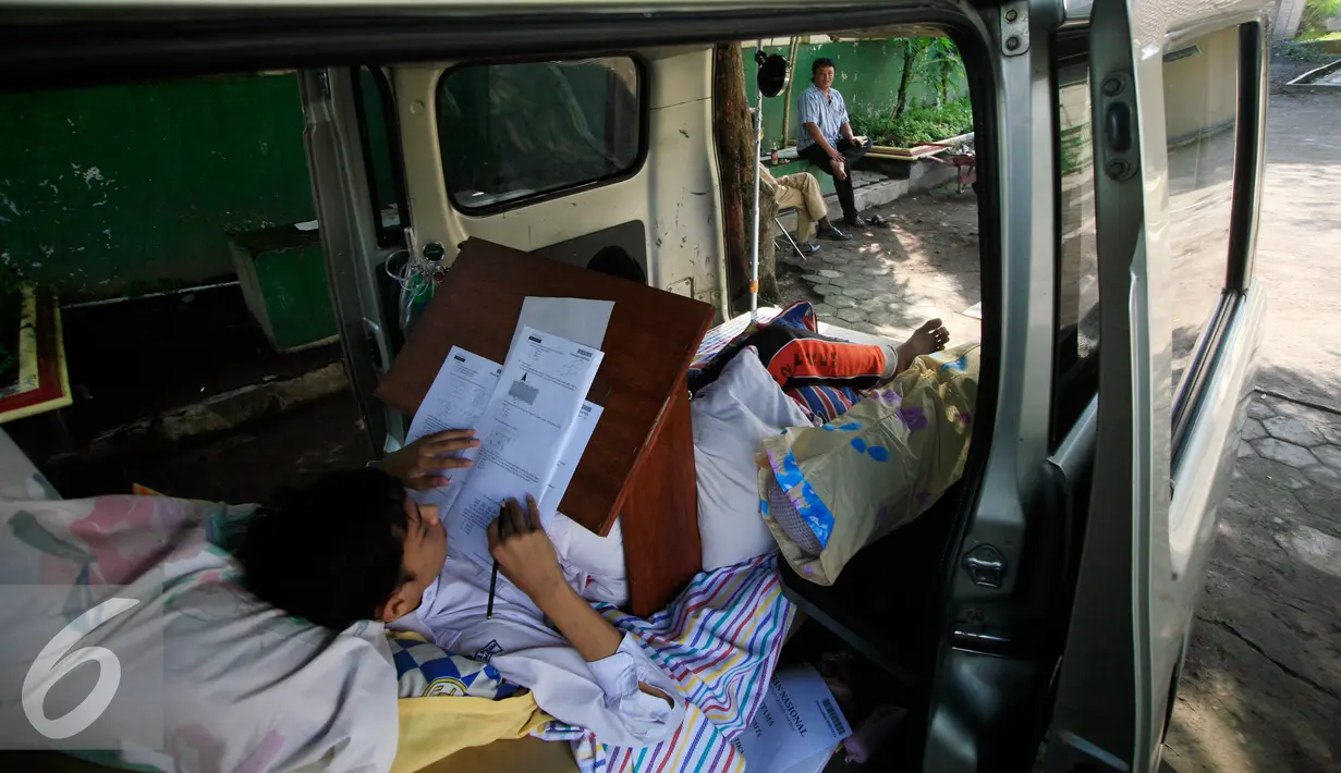 Seorang siswa SMP N 2 Pakem ,Fitrian (14) terlihat serius mengerjakan soal Ujian Nasional di halaman SMP N 2 Pakem, Sleman, (10/5). Akibat kecelakaan,Fitrian terpaksa melaksanakan UN di dalam mobil ambulans . (Liputan6.com/Boy Harjanto)