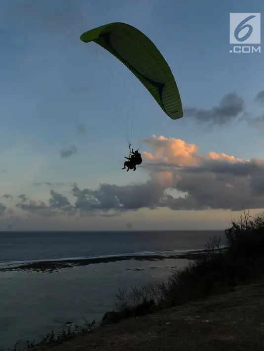 Wisatawan melakukan tandem paralayang di Bukit Riug, Nusa Dua, Bali (30/6). Kegiatan paralayang tandem dengan mengandalkan angin pantai sudah lebih dari satu tahun digemari para wisatawan mancanegara dan lokal. (Merdeka.com/Arie Basuki)