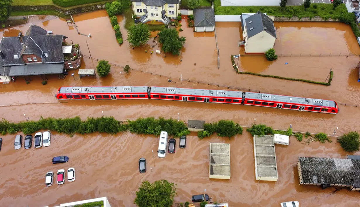 Sebuah kereta api regional terendam banjir setelah dibanjiri oleh tingginya air sungai Kyll di Kordel, Jerman, Kamis (15/7/2021). Sekitar 6.000 orang di munisipalitas Heimerzheim harus dievakuasi, sementara rumah dan harta benda mereka diterjang banjir. (Sebastian Schmitt/dpa via AP)