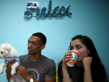 Pengunjung bermain bersama anak anjing saat mengunjungi Dog Cafe di Los Angeles, AS (7/4). Di kafe ini pengunjung dapat bermain dan mengadopsi anjing yang berada di kafe ini. (REUTERS/Lucy Nicholson)