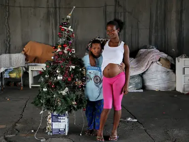 Tatiani (kanan) dan anaknya Leonardo berpose disamping pohon Natal di Sao Paulo, Brasil, (18/12). Mereka adalah keluarga tunawisma yang tinggal di bawah jembatan. (REUTERS/Nacho Doce)