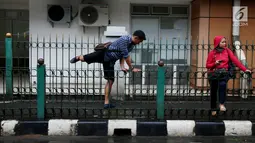 Seorang pria melompati pagar pembatas di Stasiun Cikini, Jakarta Pusat, Rabu, (20/12). Akses pintu keluar stasiun yang terlalu jauh membuat banyak penumpang yang mencari jalan pintas dengan melompat pagar satsiun. (Liputan6.com/Johan Tallo)