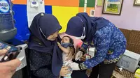 Seorang tenaga kesehatan memberikan suntikan imunisasi anak rutin di Posyandu Erma, Kelurahan Ledeng, Cidadap, Kota Bandung, Jawa Barat pada Rabu, 17 Mei 2023. (Dok Liputan6.com/Fitri Haryanti Harsono)