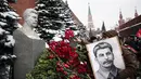 Seorang wanita memegang potret pemimpin Soviet Josef Stalin sambil meletakkan bunga di makamnya untuk memperingati 142 tahun kelahirannya di dekat Tembok Kremlin di Lapangan Merah di Moskow, Rusia, Selasa (21/12/2021). (AP Photo/Alexander Zemlanichenko)