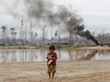 Seorang anak membawa anjingnya di depan kamp pertambangan emas ilegal yang dihancurkan polisi di zona Mega 14, Madre de Dios, Amazon selatan, Peru, (13/7/2015). Tambang emas ilegal ini termasuk dalam wilayah cagar alam hutan Amazon. (REUTERS/Janine Costa)
