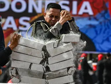Seorang anggota polisi menunjukkan kekuatan fisiknya dengan mematahkan balok beton dalam sebuah upacara yang diadakan untuk memperingati hari jadi ke-78 Kepolisian Republik Indonesia di Banda Aceh pada 1 Juli 2024. (CHAIDEER MAHYUDDIN/AFP)