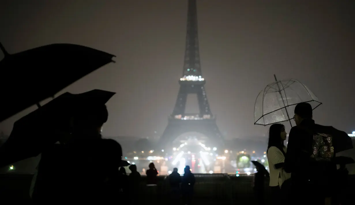 Pengunjung berkumpul di alun-alun Trocadero ketika lampu Menara Eiffel dipadamkan di Paris, Senin (2/10). Pemadaman lampu menara yang menjadi ikon Negara Prancis ini sebagai bentuk penghormatan untuk korban penembakan di Las Vegas. (AP/Kamil Zihnioglu)