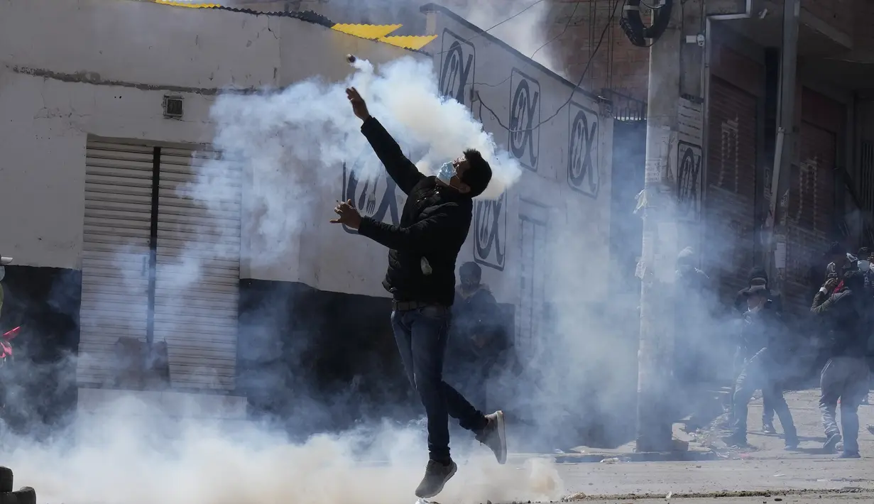 Seorang petani koka melemparkan kembali tabung gas air mata yang ditembakkan oleh polisi anti huru hara selama bentrokan di dekat pasar koka di La Paz, Bolivia, Kamis (23/9/2021). (AP Photo/Juan Karita)