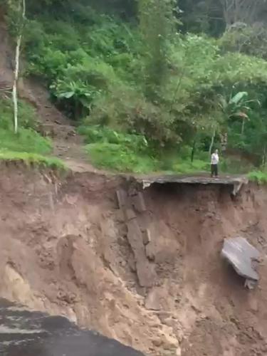 Seorang warga sekitar mengamati jalan raya penghubung dua kecamatan Cihurip dan Singajaya wilayah Garut Selatan, Jawa Barat, yang terputus akibat longsor. (Liputan6.com/Jayadi Supriadin)