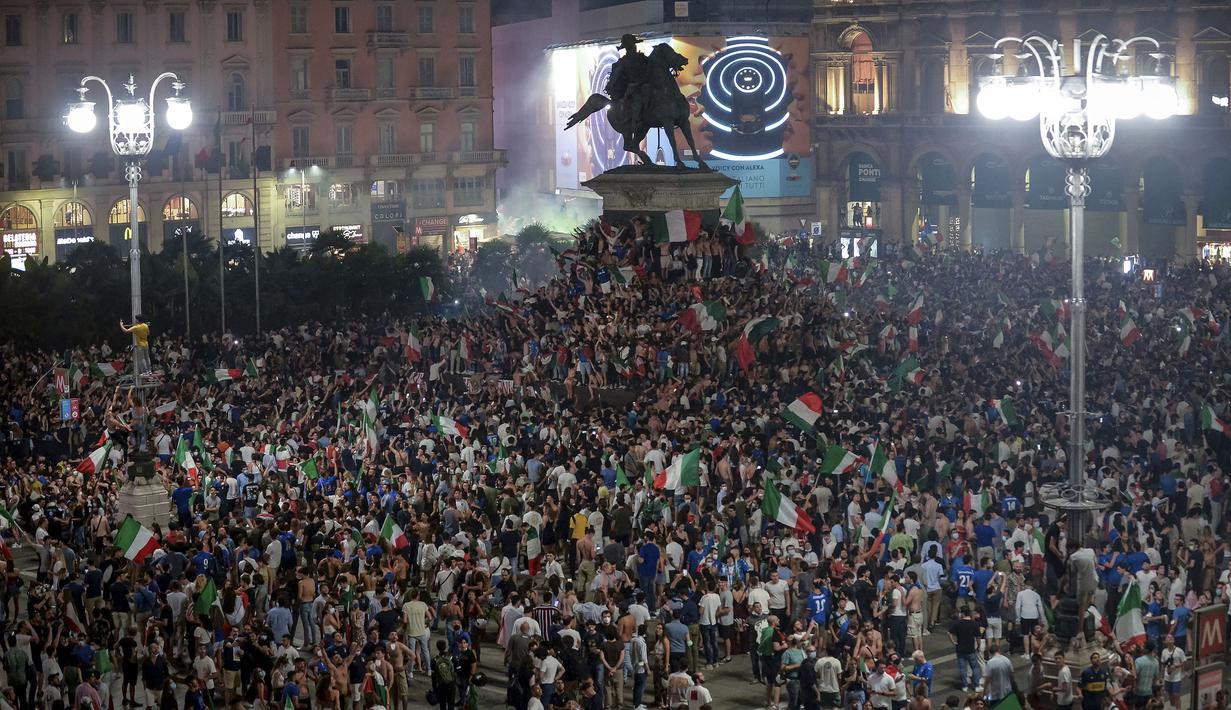 Pendukung Italia merayakan kemenangan di Piazza Duomo, Milan pada Senin (12/07/2021), setelah Italia berhasil mengalahkan Inggris pada Final Euro 2020 yang berlangsung di Stadion Wembley. Italia mengalahkan Inggris 3-2 dalam adu penalti setelah bermain imbang 1-1. (AP/Pool/Claudio Furlan)