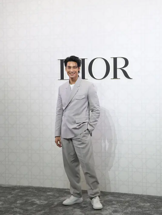 Apo tampak kenakan Double-Breasted Jacket with Buttoned Strap seharga Rp62jutaan. Dipadu dengan celana abu-abu dan sneakers putih dari Dior