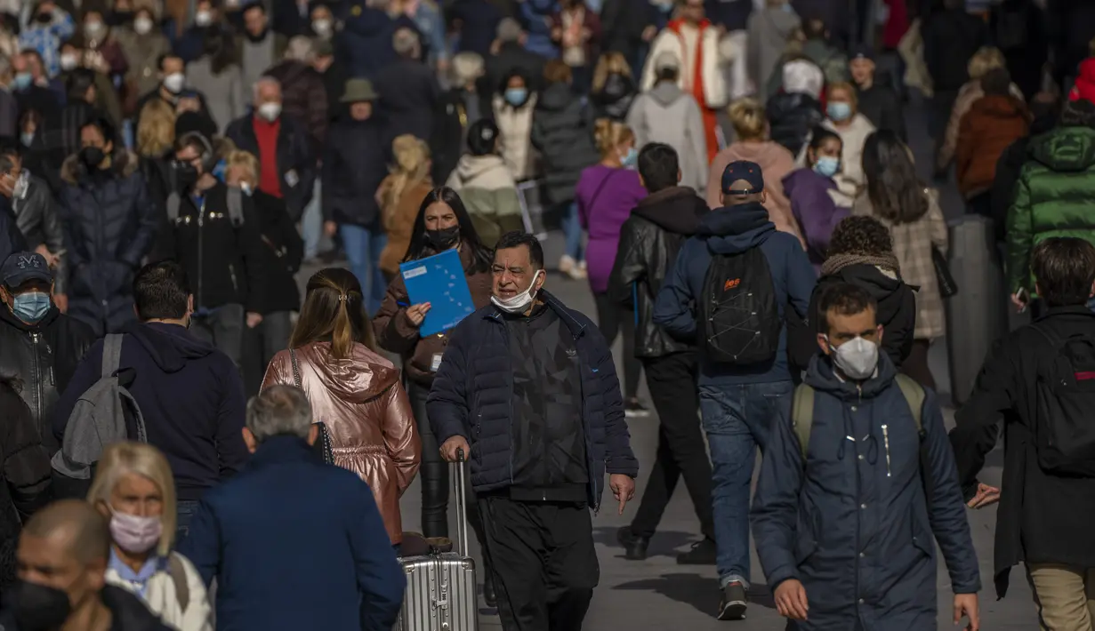 Orang-orang, beberapa dari mereka tanpa masker, berjalan di sepanjang jalan di pusat kota Madrid, Kamis (10//2/2022). Warga Spanyol untuk pertama kalinya dalam hampir dua bulan diperbolehkan tidak menggunakan masker di luar ruangan setelah peraturan terkait hal itu dicabut. (AP Photo/Manu Fernandez)